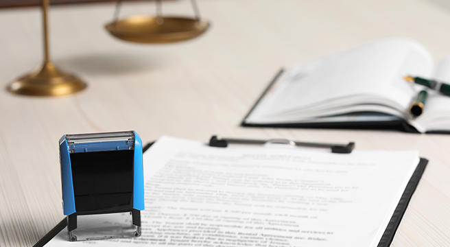 Image: Photo of a contract, clip board, and stamp